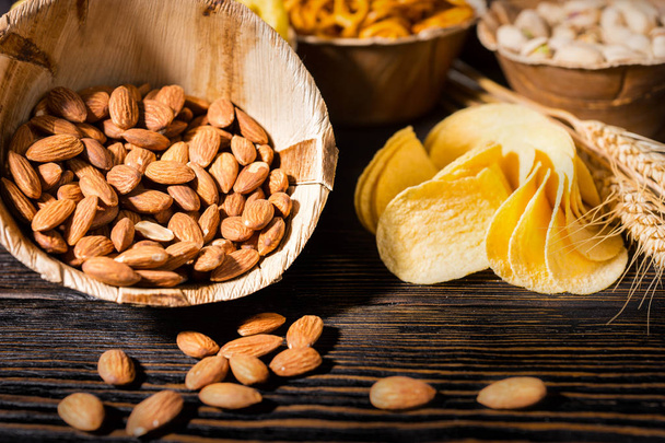 Close up of wooden plate with almonds near wooden plates with sn - Foto, afbeelding