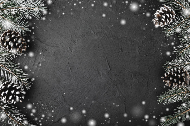 Xmas theme with fir branches, evergreen pines, on snowy black, stone background viewed from above, greeting card with space for text - Photo, image