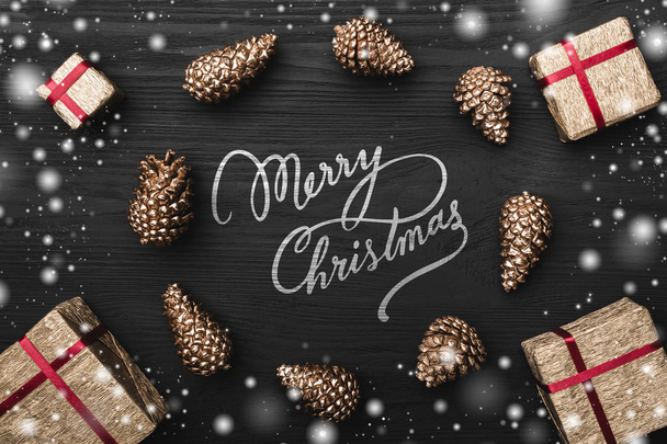 Cercle de pins de sapin doré et cadeau, boîtes cadeaux, Joyeux Noël signe sur neige noire, fond en bois sombre, avec espace pour le texte carte de vœux de Noël
 - Photo, image