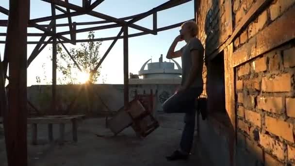 Młody człowiek stoi na placu budowy i połączeń - Materiał filmowy, wideo