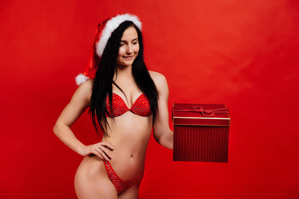 Christmas, New Years holidays.. Sexy sports beautiful girl in bikini santa claus with gift box - 写真・画像