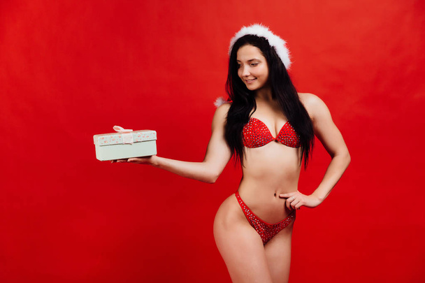 Christmas, New Years holidays.. Sexy sports beautiful girl in bikini santa claus with gift box - Foto, imagen