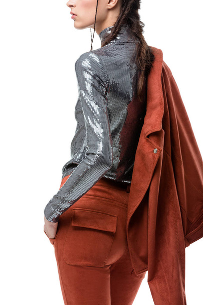 Foto de cerca de la niña de pie desde atrás en chaqueta de gamuza marrón claro y parte superior de plata con lentejuelas sobre fondo blanco
 - Foto, imagen