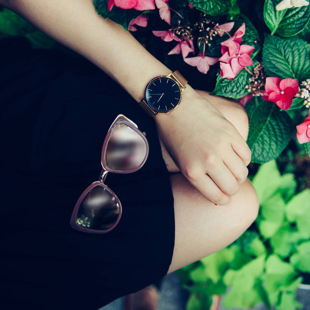 Female accessories concept. Sunglasses, golden watch and black skirt. - Foto, Imagem