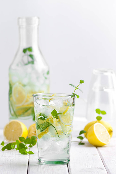 Lemonade in a glass cup on a white wooden table - Fotoğraf, Görsel