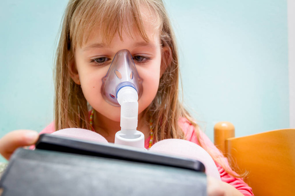Little girl is gaming on mobile phone until using an inhaler - Photo, image