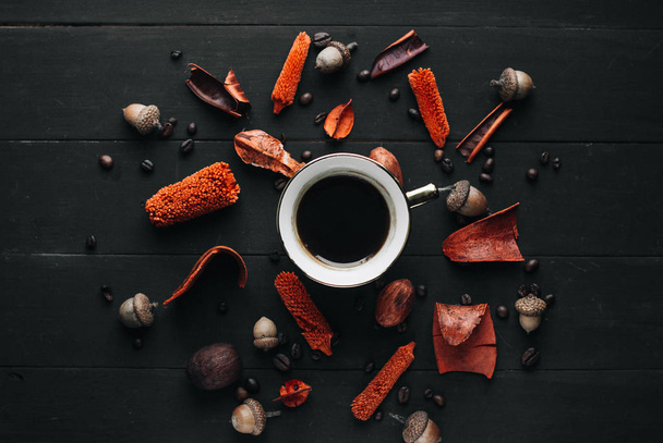 Cup of hot coffee with dried herbs and coffee beans on dark wooden table - Photo, Image