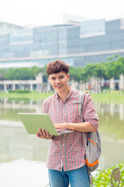 Привабливий чоловік азіатський студент використовує ноутбук в кампусі
 - Фото, зображення