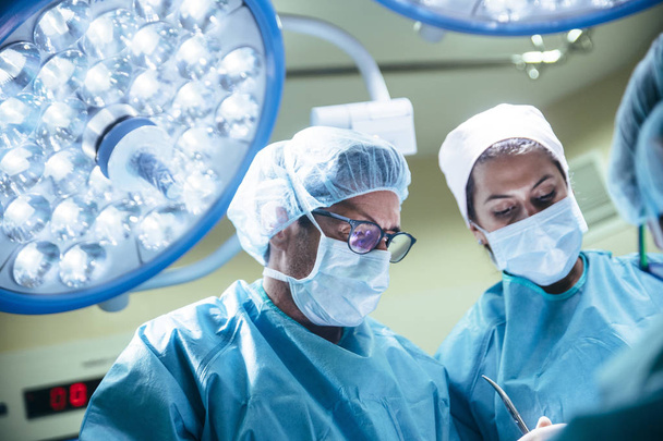 Muotokuva lääkäreistä naamioissa katsomassa potilasta leikkaussalissa
 - Valokuva, kuva