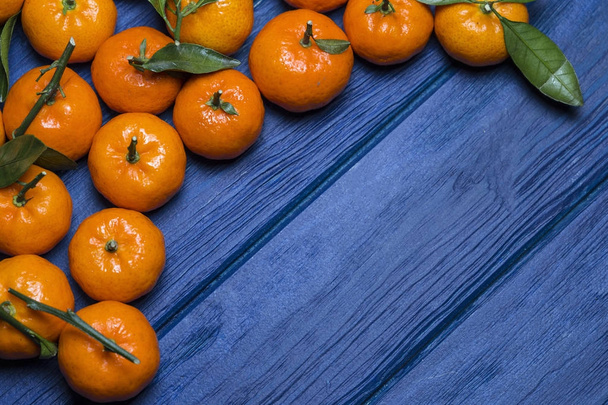 orange juicy mandarins (mandarins) with green leaves on a blue w - Photo, image