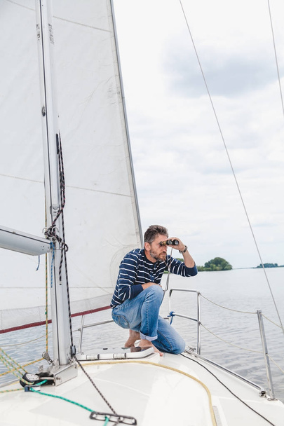 man sits on sailing yacht and looks through binoculars - Foto, Imagem