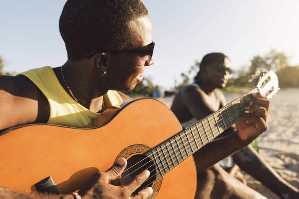 Two cuban friends having fun in the beach with his guitar. - Photo, image