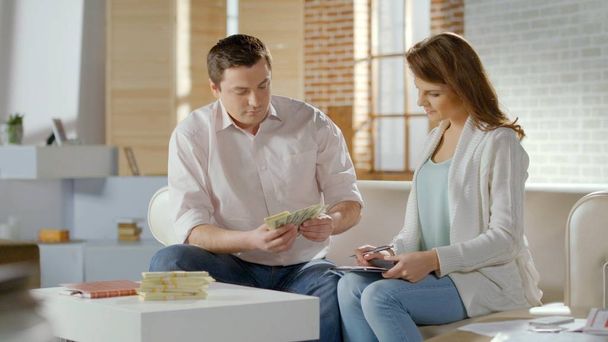 Successful married couple counting cash at home, family budget money, savings - Valokuva, kuva