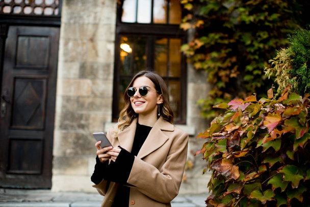 Moderne Frau nutzt Handy im Herbst im Freien - Foto, Bild