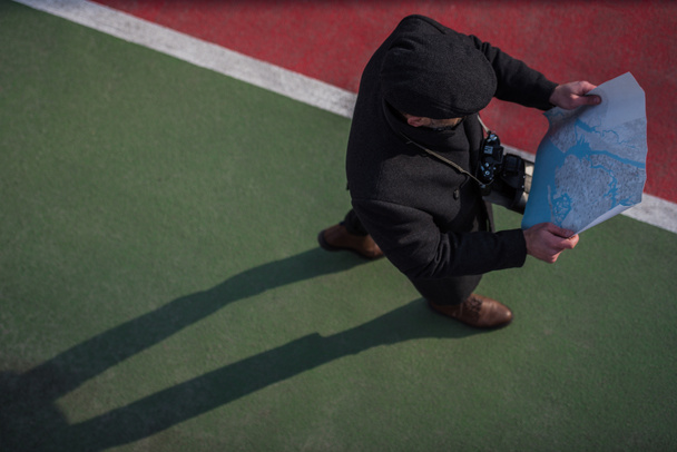 vysoký úhel pohledu turista v kabátu a čepice chůzi s mapou - Fotografie, Obrázek