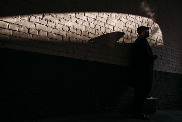 silhouette of man smoking in front of brick wall - Фото, зображення