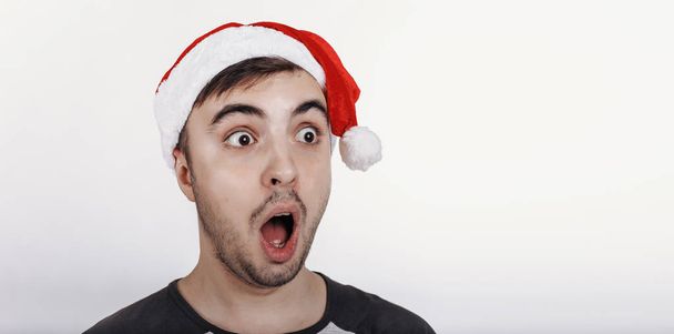 Il giovane con il cappello da Babbo Natale molto sorpreso da qualcosa
 - Foto, immagini