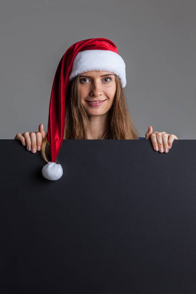 Woman in santa christmas hat holding placard - Фото, зображення