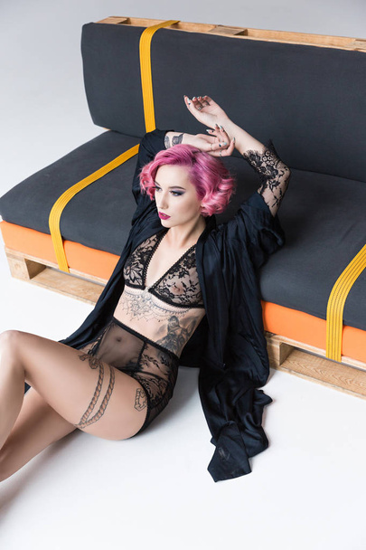 seductive tattoed pin up girl in transparent lingerie posing on couch - Фото, изображение