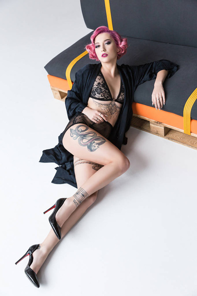 seductive tattoed pin up girl in transparent lingerie posing at couch - Foto, imagen