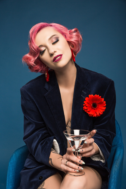beautiful tattoed pin up girl in jacket with boutonniere and wineglass infront of blue background - Foto, imagen