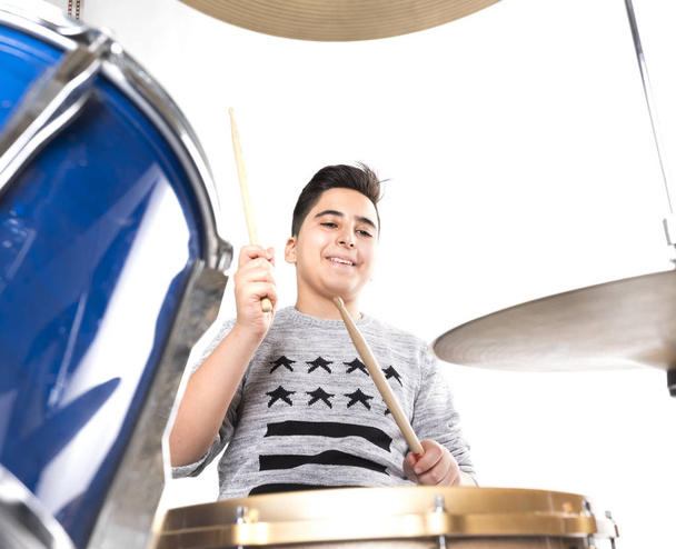 teen boy at drumset in studio against white background - Photo, Image