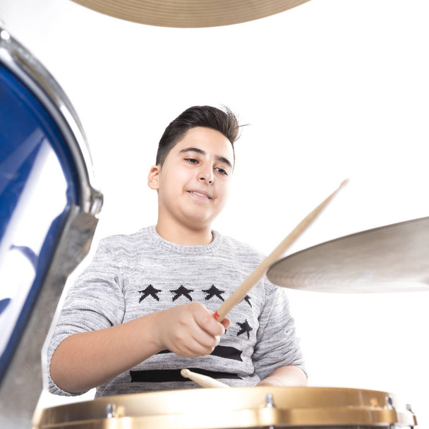 teen boy at drumset in studio against white background - Photo, Image
