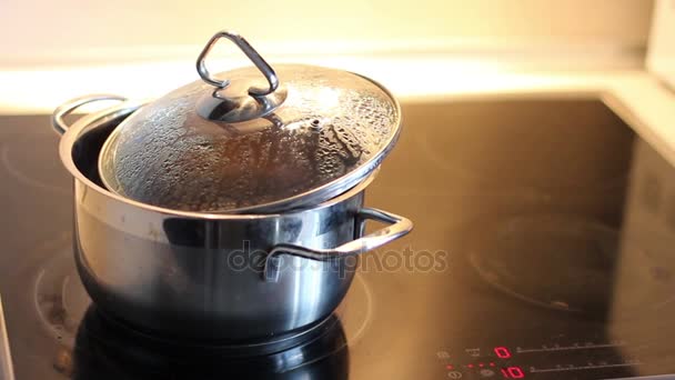  pan is on the cooking plate. Buckwheat porridge is cooked in a pan. The water in the pot is boiling and bubbling - Filmati, video