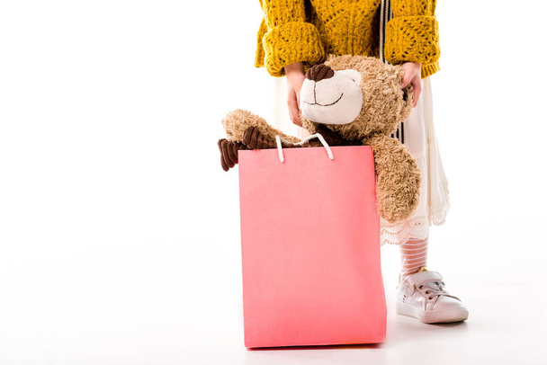 περικομμένη εικόνα του παιδιού που στέκεται με αρκουδάκι στην τσάντα για ψώνια σε λευκό - Φωτογραφία, εικόνα