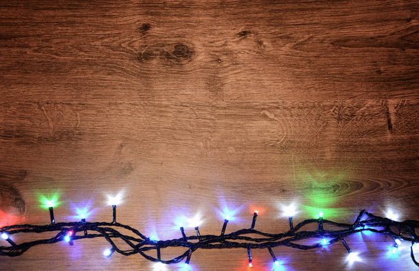 Vánoční elektrický věnec na dřevěné pozadí. O jasné žárovky - Fotografie, Obrázek
