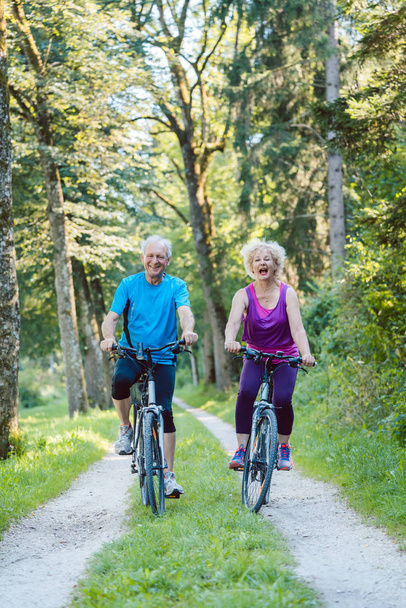 Felice e attiva coppia di anziani in bicicletta all'aperto in p
 - Foto, immagini