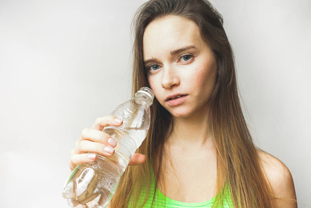 jovem de cabelos longos bela menina segurando uma garrafa de água limpa nas mãos
 - Foto, Imagem