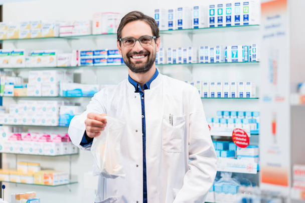 Apteekkari apteekissa, joka myy lääkkeitä pussissa
 - Valokuva, kuva