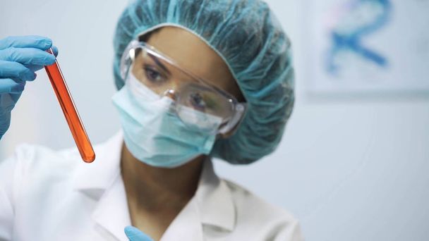Médico de raça mista analisando novo líquido vacinal em tubo, perícia médica
 - Foto, Imagem