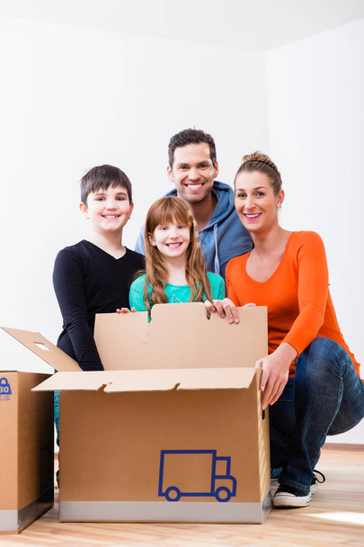Familie packt Umzugskartons im neuen Zuhause aus - Foto, Bild