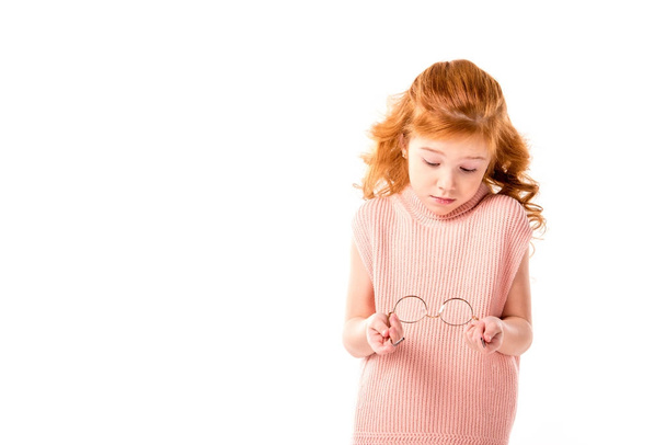 κοκκινομάλλα παιδί βλέπει γυαλιά στα χέρια που απομονώνονται σε λευκό - Φωτογραφία, εικόνα