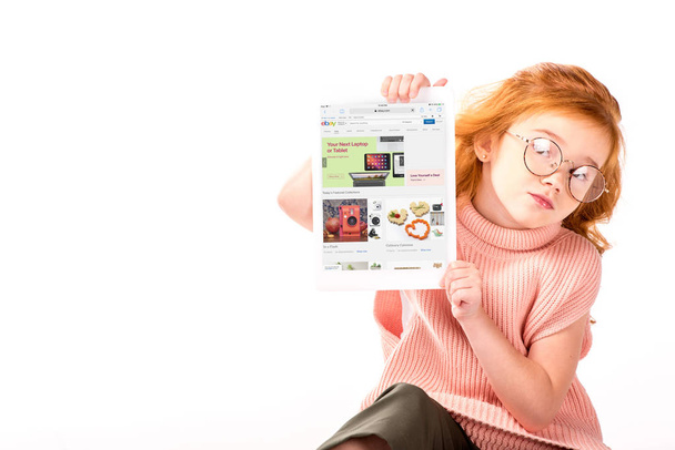 red hair kid sitting and showing loaded ebay page on tablet isolated on white - Valokuva, kuva