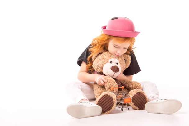 kid playing with teddy bear and shopping car toy on white - Фото, зображення