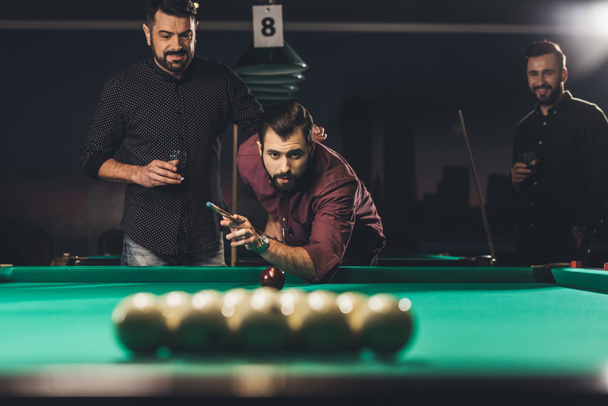 handsome man playing in pool at bar with friends - Photo, Image