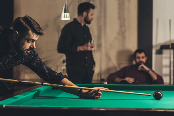 успешный красивый мужчина играет в бильярд в баре с друзьями
 - Фото, изображение