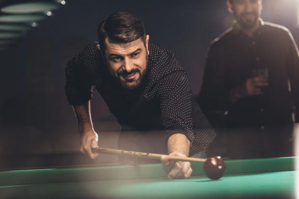 successful man playing in pool at bar with friend - Photo, Image