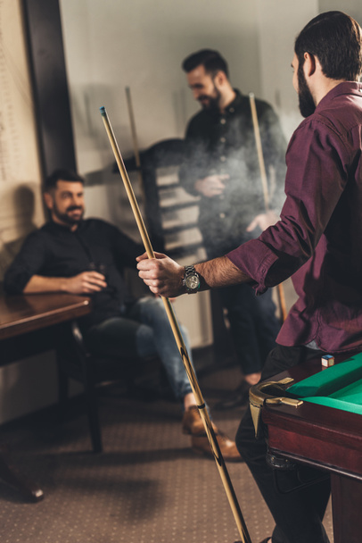gezelschap van gelukkig mannen met drankjes en cues in billiard bar  - Foto, afbeelding