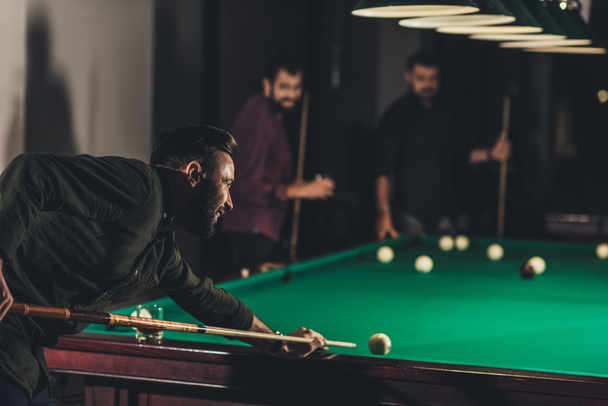 company of successful handsome men playing in pool at bar - Photo, Image