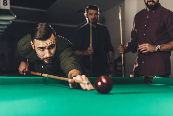 young successful handsome man playing in russian pool at bar with friends - Fotó, kép