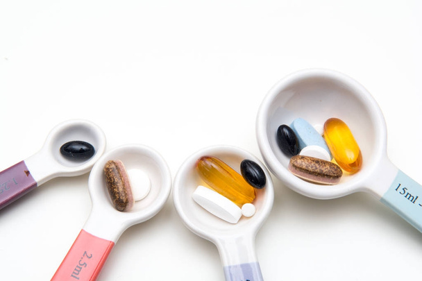 Medikamentenpillen und Tabletten mit Löffeln zur Messung der Medikamentendosis. - Foto, Bild