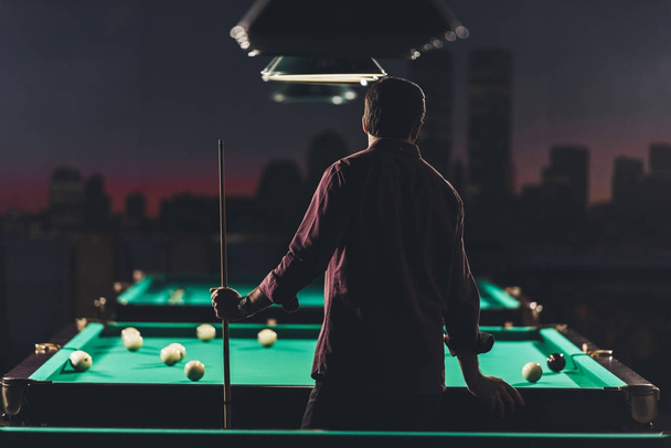 back view of successful man standing beside pool table with at bar - Photo, Image