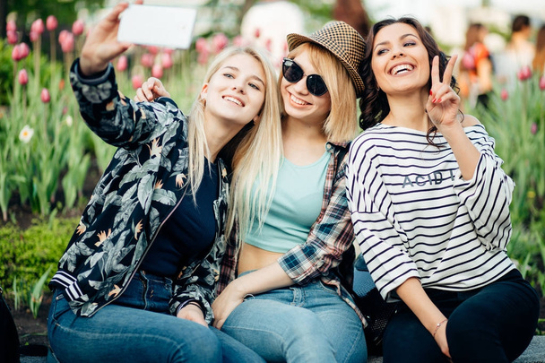 Summer outdoor portrait of three friends fun girls taking photos with smartphone - Fotografie, Obrázek