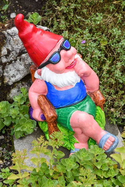 Garden gnome sitting in a chair on a garden - Photo, Image