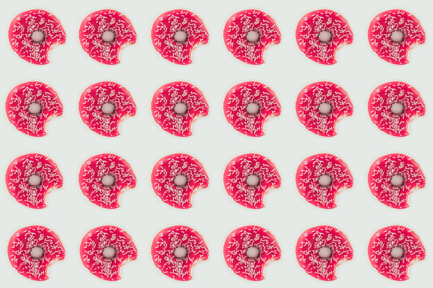 bovenaanzicht van naadloze patroon gebeten roze donuts geïsoleerd op wit - Foto, afbeelding