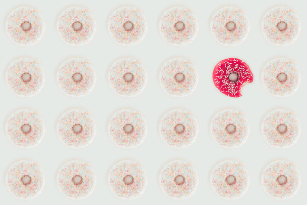 bovenaanzicht van naadloze patroon met witte en roze donuts geïsoleerd op wit - Foto, afbeelding